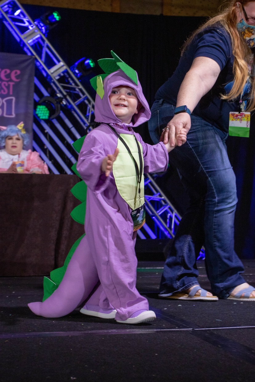 A child cosplaying My Little Pony character Spike on stage